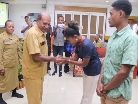 Staff Ahli Walikota Jayapura Sem Stenly Merauje, menyematkan tanda peserta pramusaji yang digagas Dinas Pariwisata